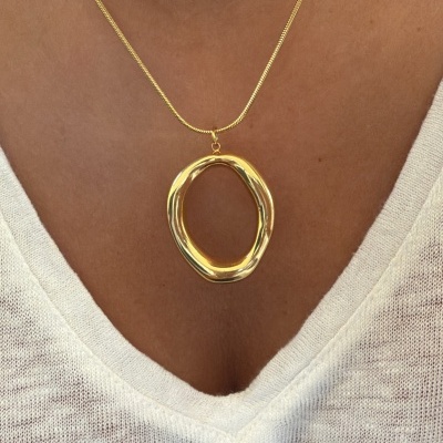 Colar dourado com pendente oval irregular e camisola branca de malha.