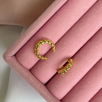 Brincos dourados texturizados numa caixa de veludo rosa