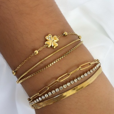 Conjunto de seis pulseiras douradas com diferentes estilos no braço sobre fundo branco