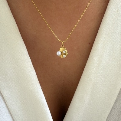 Colar dourado com pendente em forma de mão com pedras