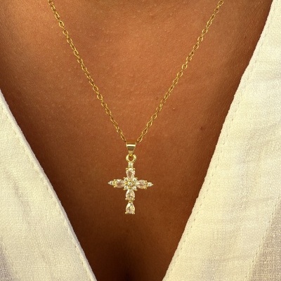 Colar dourado com pendente em forma de cruz com pedras brilhantes