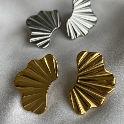 Brincos ondulados dourados e prateados sobre tecido branco