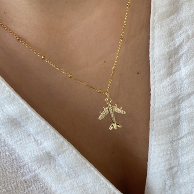colar dourado com pendente de avião e camisa branca