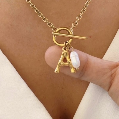 Colar dourado com pendente letra A e pérola em pescoço