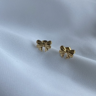 Par de brincos em formato de laço dourados sobre fundo branco