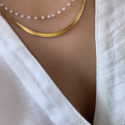 Colares de pérolas e dourado usados com camisa branca