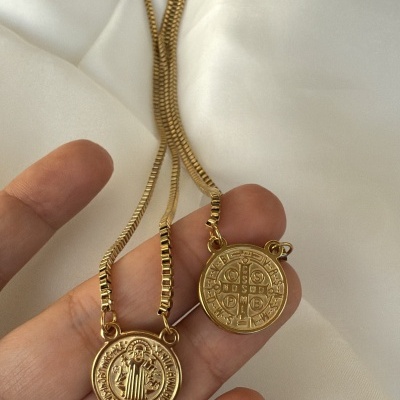 Colares com medalhões dourados e correntes finas sobre fundo branco