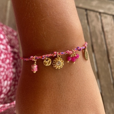 pulseira trançada rosa com pendentes dourados e pedras rosas no pulso