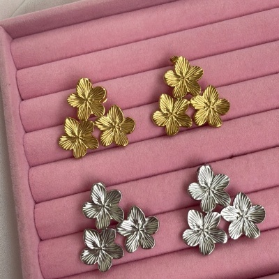 Brincos florais dourados e prateados numa caixa de veludo rosa