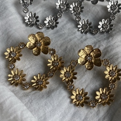 Brincos redondos florais em metal dourado e prateado sobre tecido branco