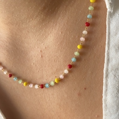 Colar de contas coloridas usado no pescoço com roupa branca