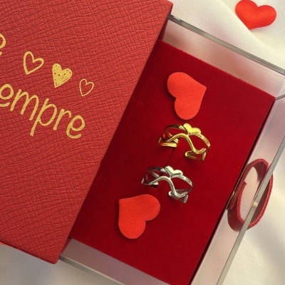 Conjunto de alianças dourada e prateada com corações em caixa vermelha com tampa texto dourado