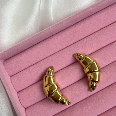 Brincos dourados croissant em almofada rosa de veludo