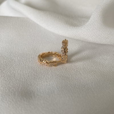 Anel dourado com pedras sobre tecido branco suave