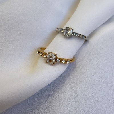 Anéis finos dourado e prateado com pedras sobre tecido branco