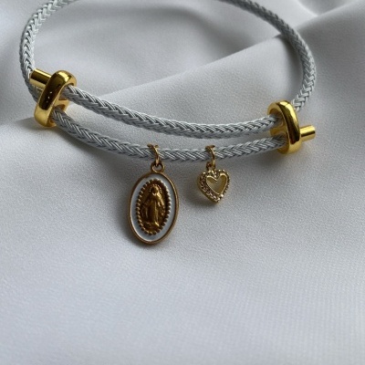 Pulseira dupla branca com pendentes dourados em fundo branco.