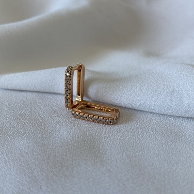 Brinco quadrado dourado com pedras brilhantes sobre tecido branco