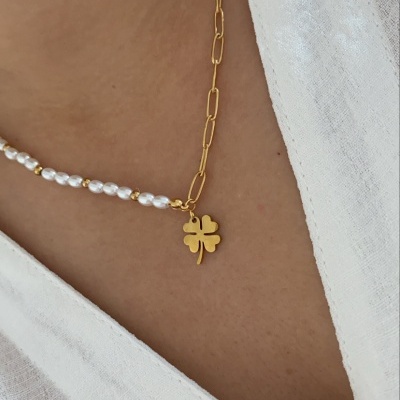 Colar feminino com correntes douradas, pérolas brancas e pendente de trevo dourado sobre pele e camisa branca