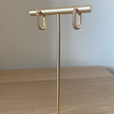 Brincos argola dourados com pedras brilhantes num suporte dourado