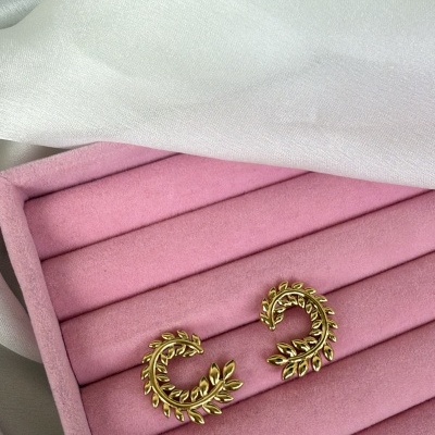 Brincos dourados em forma de folhas em caixa rosa de veludo