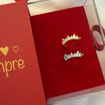 Brincos dourado e prateado com pedras em caixa vermelha texturada com texto 'sempre'