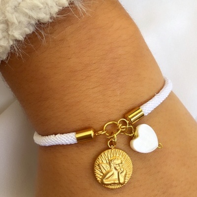 Pulseira branca com pendentes dourado e coração branco num pulso