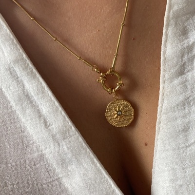 Colar dourado com pendente redondo texturado usado com vestido branco