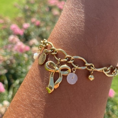 Pulseira dourada com pendentes num pulso ao ar livre