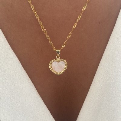 Colar dourado com pendente de coração com pedra rosa.