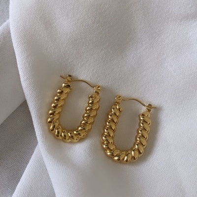 Brincos de argola dourados texturizados sobre tecido branco
