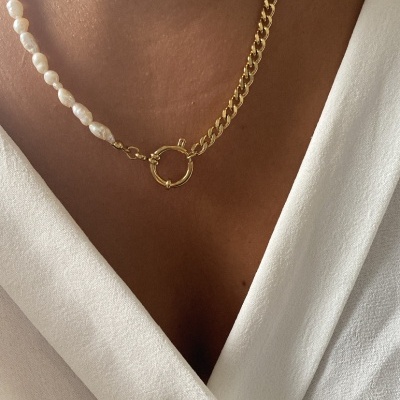 Colar metade corrente dourada e metade pérolas brancas sobre decote branco.