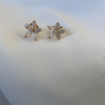 Brincos florais com pedras brilhantes sobre tecido branco