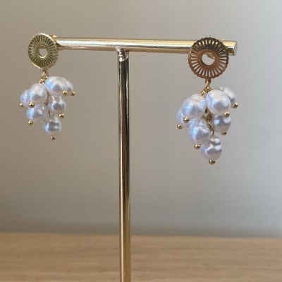 Brincos dourados com pérolas em suporte de madeira