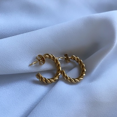 Brincos de argola dourados com textura torcida sobre tecido branco