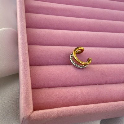 Anel dourado com pedras transparente numa caixa de veludo rosa sobre tecido branco