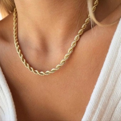 Colar dourado com corrente torcida em pescoço de pessoa com roupa branca