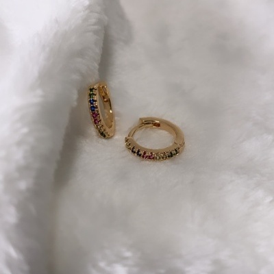 Brincos argola dourados com pedras coloridas sobre tecido branco