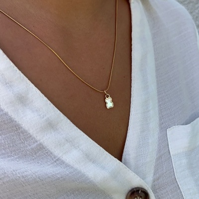 Colar dourado com pendente em silhueta e camisa branca com botões