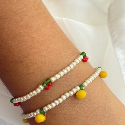 Braceletes com contas brancas e detalhes coloridos no pulso