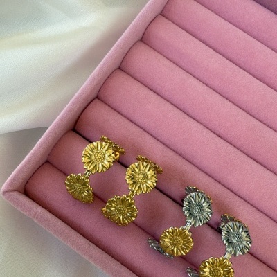 Dois pares de brincos de flores em caixa rosa sobre tecido branco