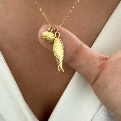 Colar dourado com pendentes de peixe e concha em roupa branca