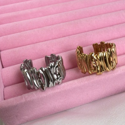 Dois anéis metálicos, um prateado e outro dourado, em caixa rosa com tecido branco.