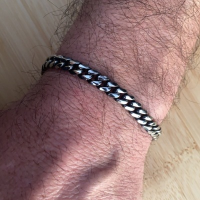 Pulseira de metal prateado com elos grossos entrelaçados no pulso