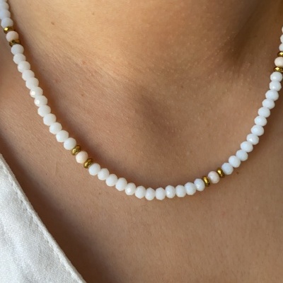 Colar de contas brancas e douradas ao redor do pescoço