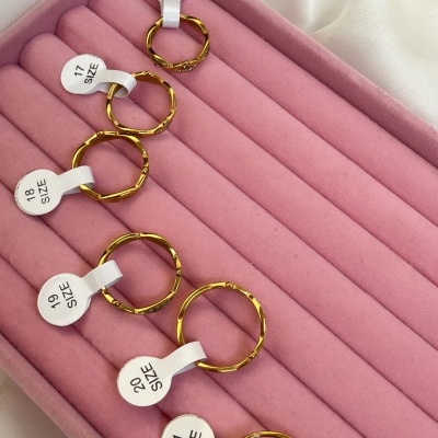 Conjunto de seis anéis dourados em caixa rosa com etiquetas de tamanho