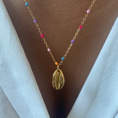 Colar dourado com contas coloridas e pendente concha sobre pele e roupa branca