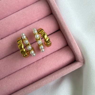 Brincos dourados com pérolas numa caixa rosa de veludo