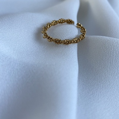 Anel dourado torcido sobre tecido branco