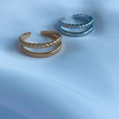 Dois anéis metálicos, dourado e prateado, sobre tecido branco