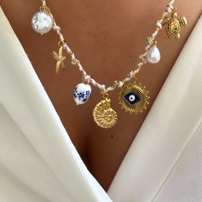 Colar com vários pendentes dourados e em branco, usado sobre uma blusa branca.